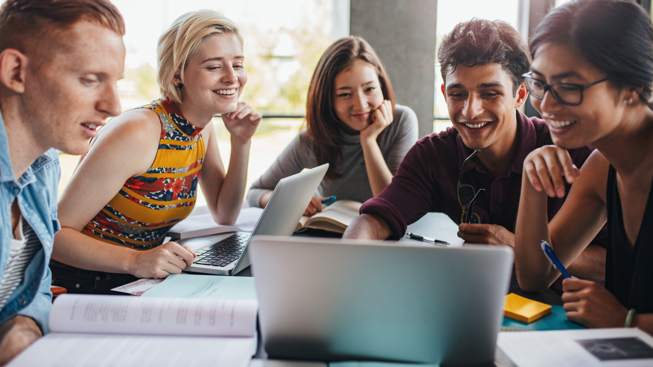 A group of students looking at a laptop and smiling