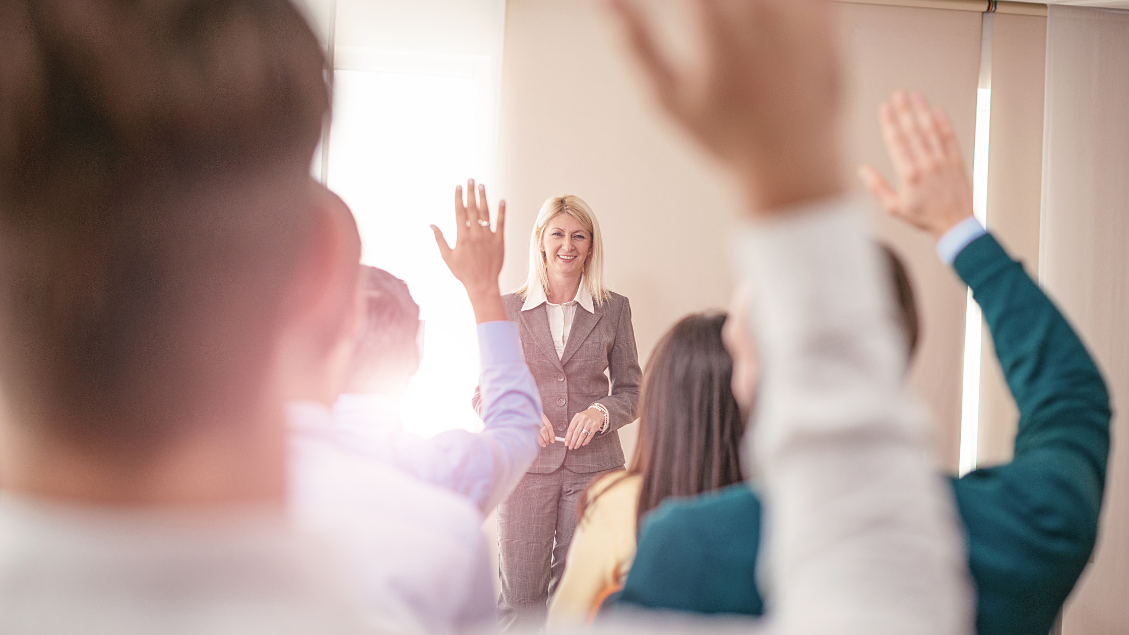 Professor teaching class and students raising hands to participate